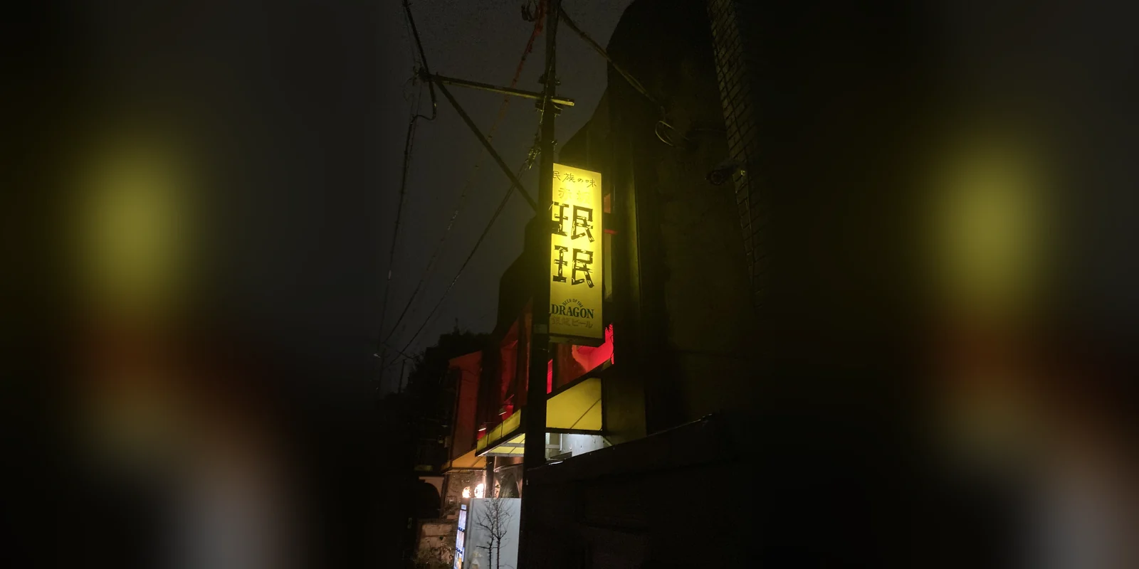 夜の赤坂珉珉の看板。黄色く光る縦長の看板に「民族の味 赤坂 珉珉」の文字