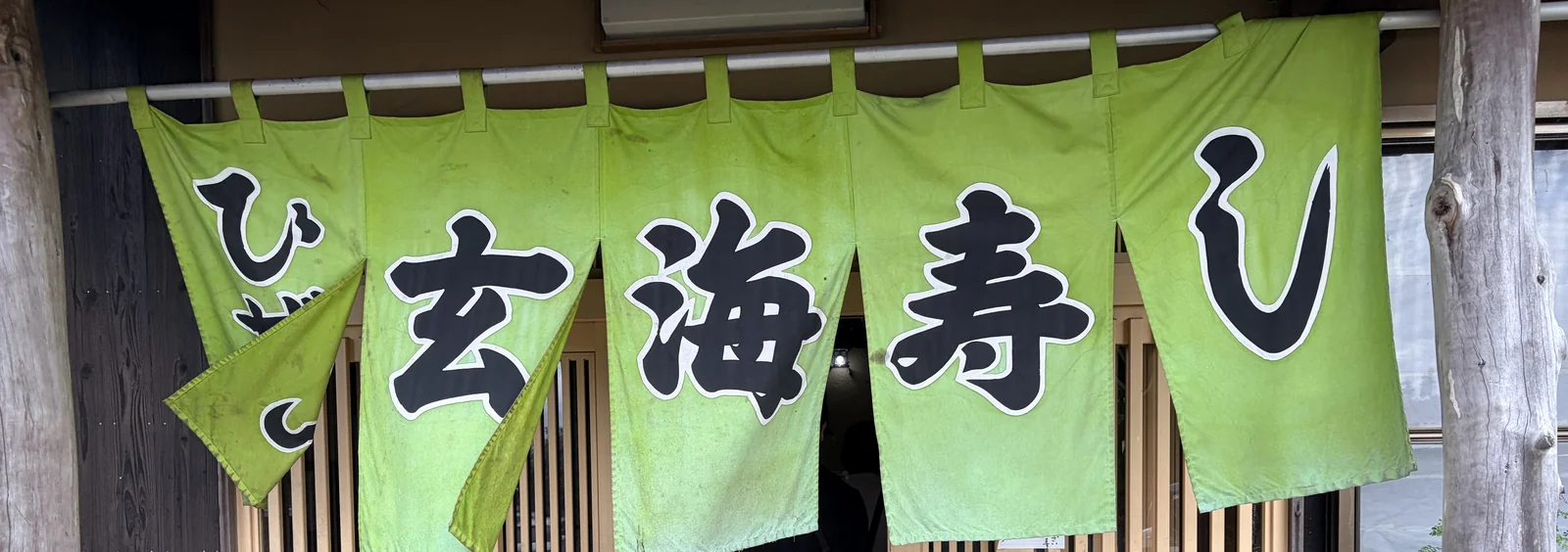 「ひぜん玄海寿し」と染め抜かれた黄緑色の暖簾。5枚に分かれ、奥に木の格子戸が見える