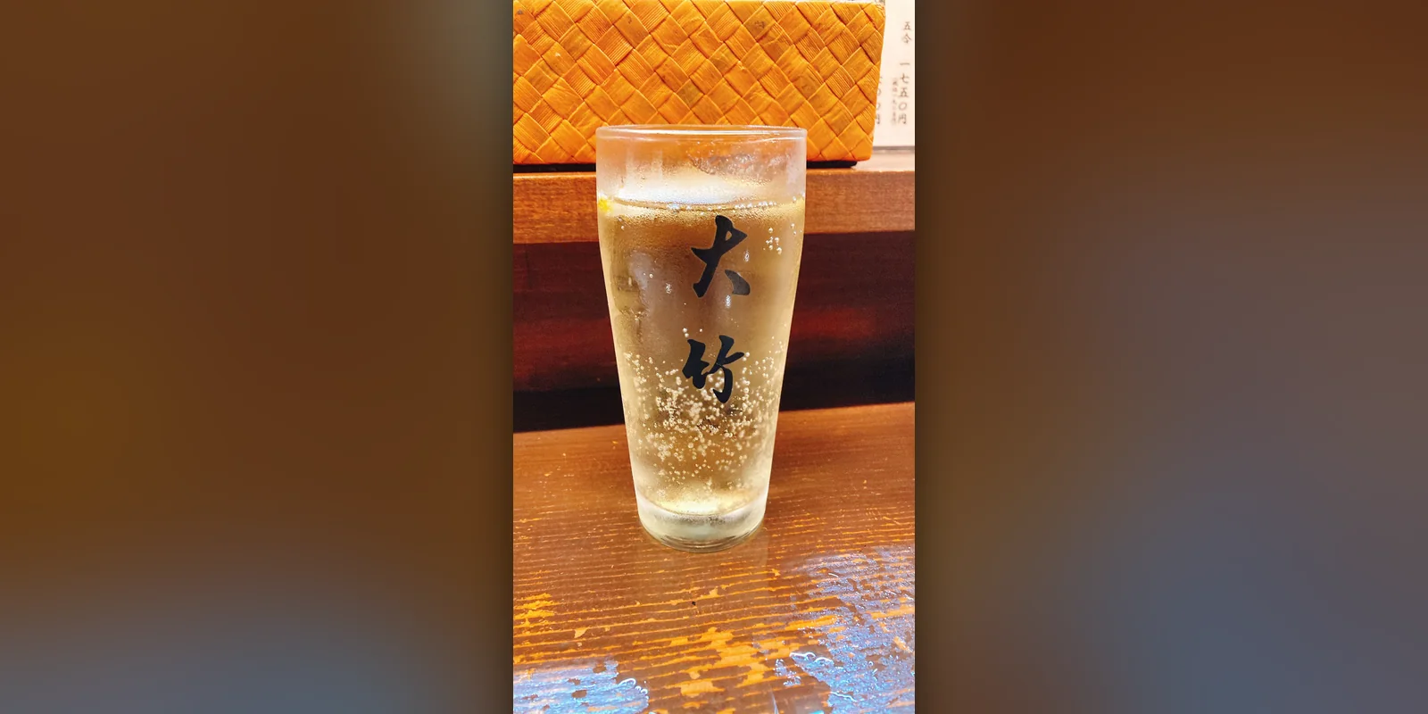小岩のもつ焼き店「大竹」のボール（下町ハイボール）。黒い文字で店名が入ったグラスに、うっすら琥珀色の液体と細かい炭酸の泡