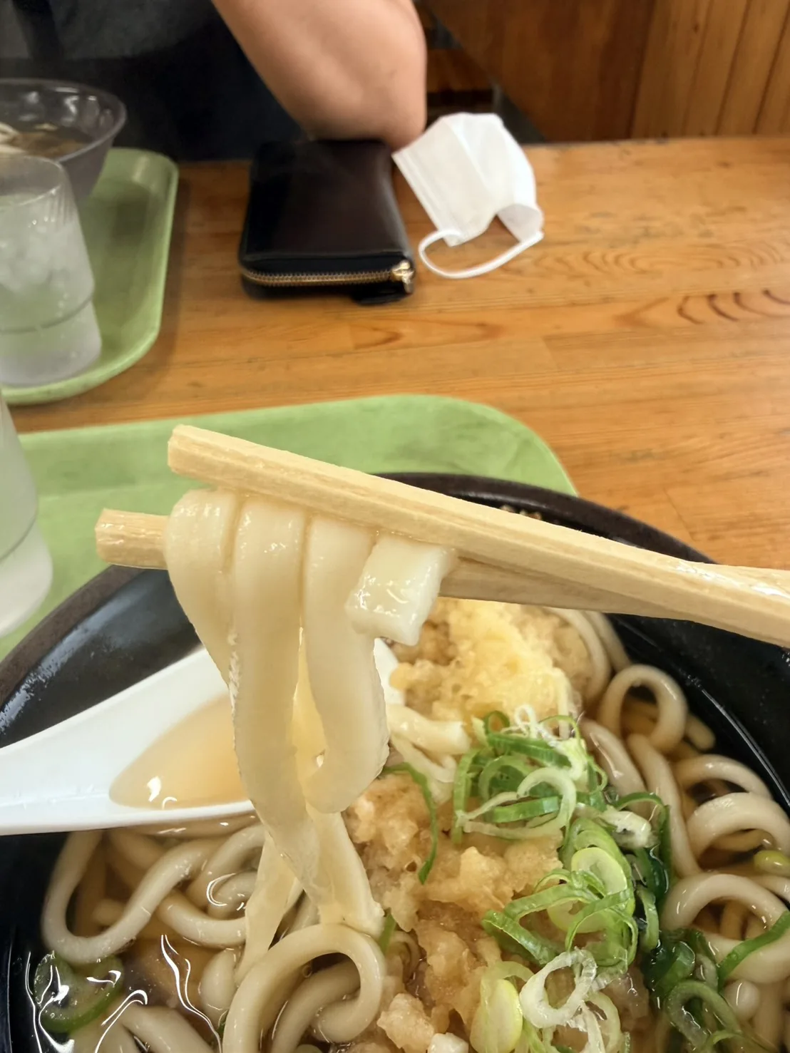 箸で持ち上げた豊吉うどんの麺。太めで角のある断面をしており、重みでゆるやかにたわんでいる