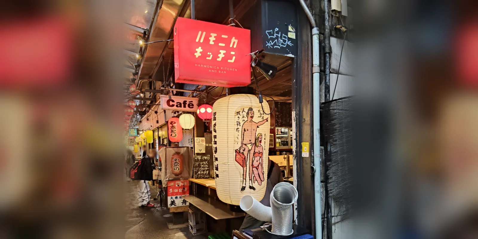 吉祥寺ハーモニカ横丁の路地。赤い看板と手描きの絵が入った白い大提灯